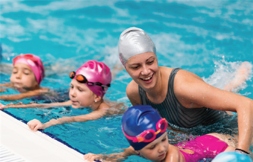 Swim instructor teaching young children 